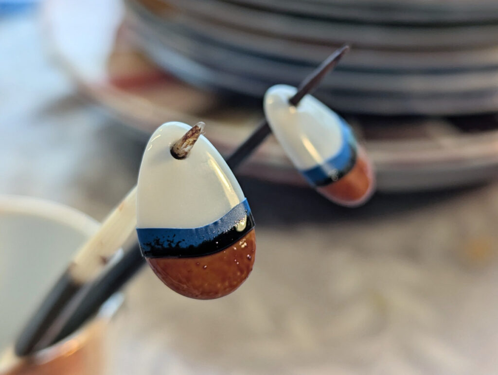 Photo prise lors de l'atelier peinture sur porcelaine montrant les breloques en porcelaine après la pose de l'or