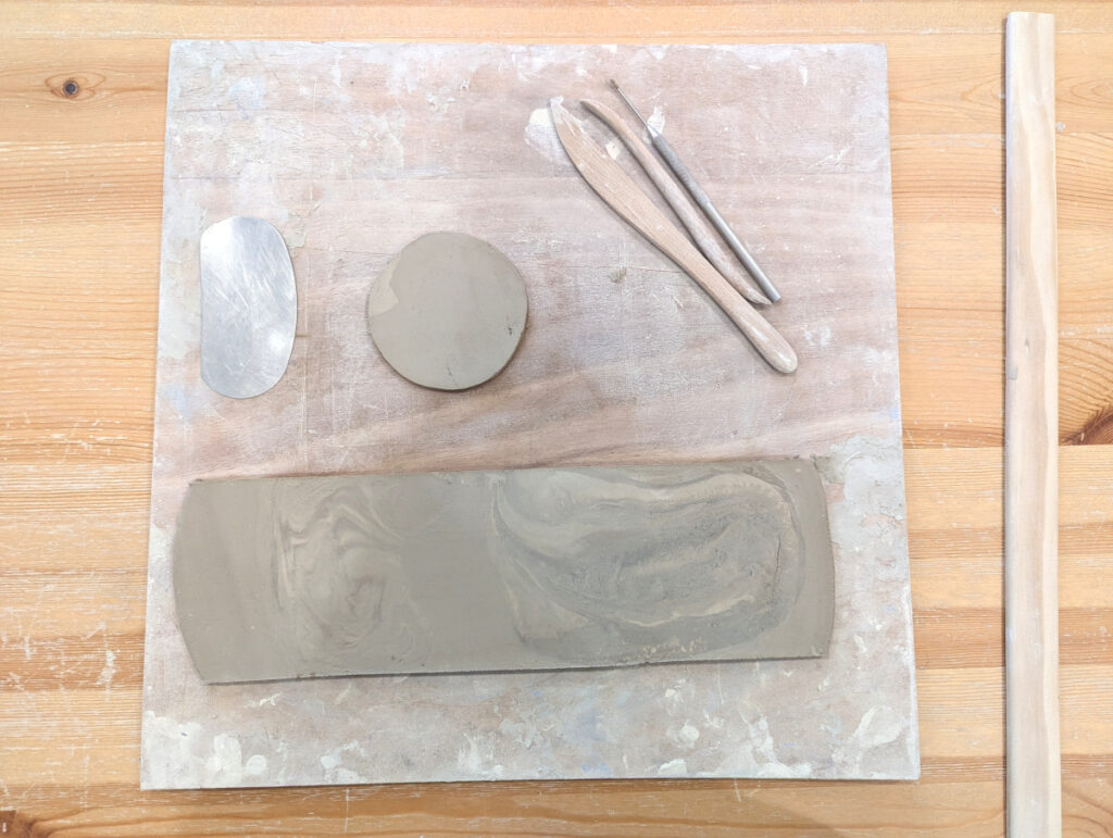 Photo montrant le fond et la paroi, ainsi que quelques outils nécessaires pour apprendre comment faire un mug sans tour