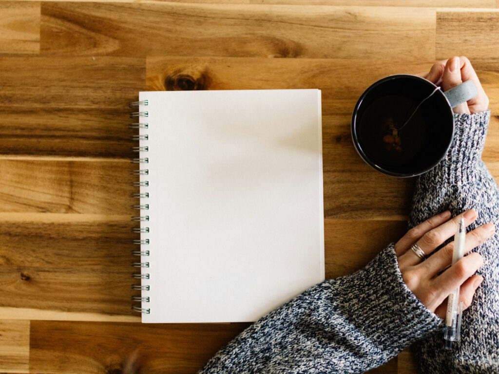 Femme devant un cahier une tasse à la main pour illustrer un article sur comment créer une bucket list pour ses 40 ans